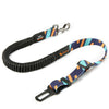 An adjustable shock-absorbing dog seatbelt with a black body, and a pattern of orange and blue geometric shapes on a portion of the fabric.
