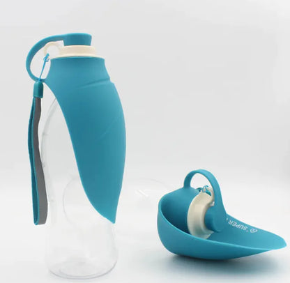 A portable pet water bottle with a flip-top lid, partially filled with water, and an attached strap for carrying. The bottle appears to be made of clear plastic and the lid is blue